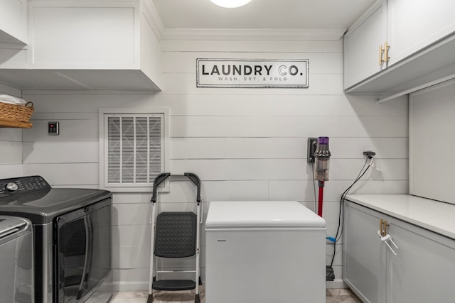 washroom featuring cabinets, separate washer and dryer, ornamental molding, and wooden walls