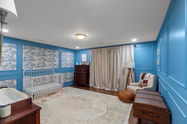 bedroom with dark hardwood / wood-style flooring and a nursery area