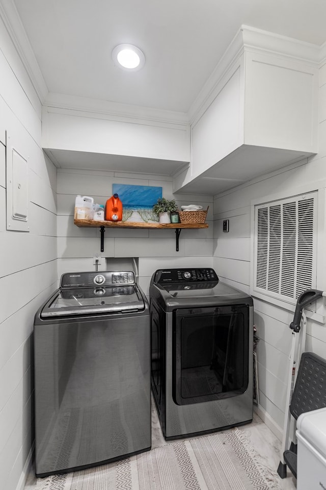 laundry room with crown molding, wood walls, and independent washer and dryer