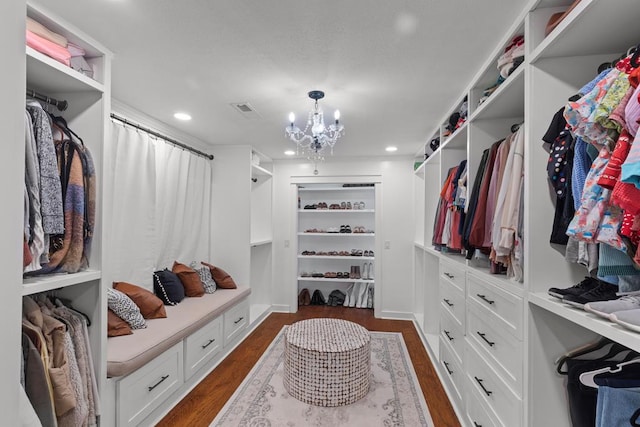 walk in closet featuring a chandelier and dark hardwood / wood-style floors