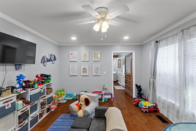 rec room with ornamental molding, ceiling fan, and dark wood-type flooring