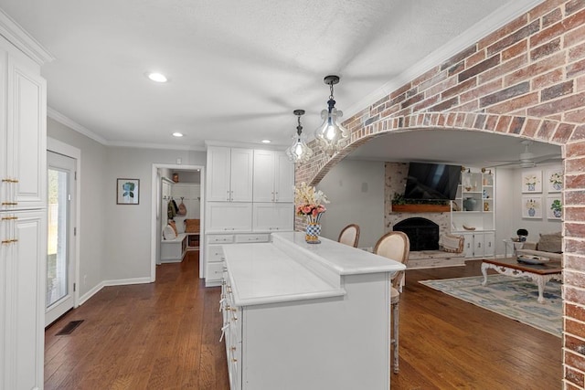 kitchen featuring a breakfast bar, pendant lighting, dark hardwood / wood-style floors, and a fireplace