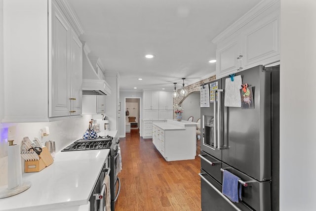 kitchen featuring white cabinetry, light hardwood / wood-style flooring, crown molding, a kitchen island, and appliances with stainless steel finishes