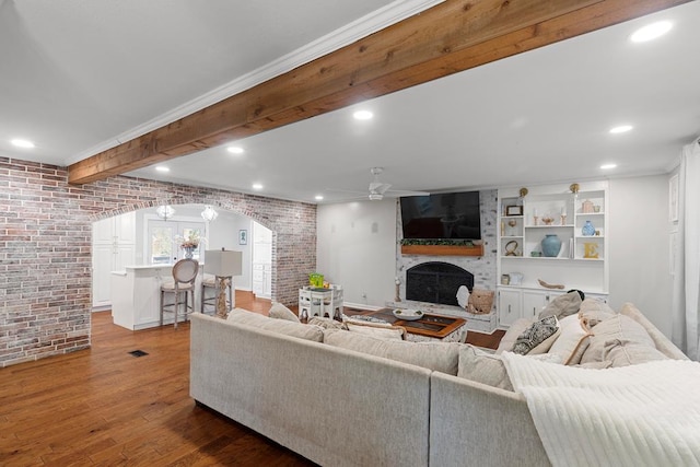 living room with brick wall, a large fireplace, ceiling fan, crown molding, and hardwood / wood-style flooring