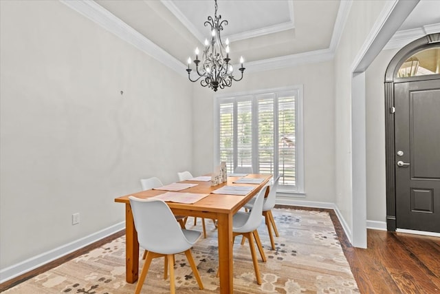 dining area with baseboards, wood finished floors, an inviting chandelier, and a tray ceiling