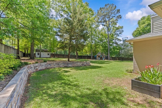 view of yard with a fenced backyard, an outbuilding, a storage shed, and a playground