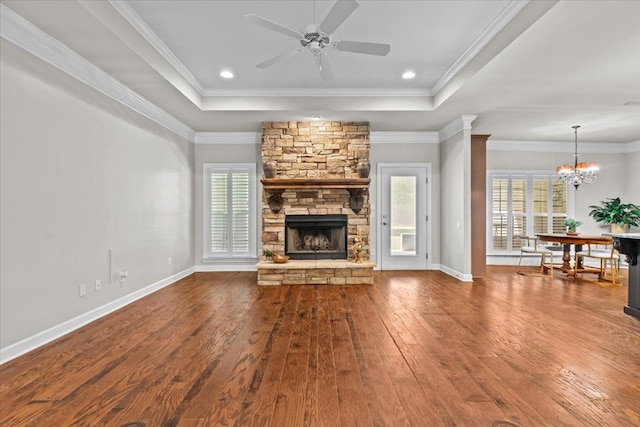 unfurnished living room with ceiling fan with notable chandelier, a fireplace, wood finished floors, and a wealth of natural light