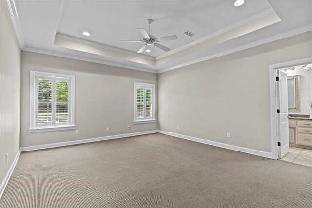 empty room with a tray ceiling, plenty of natural light, crown molding, and ceiling fan