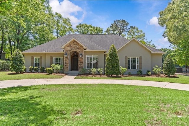 single story home featuring roof with shingles, a front yard, and stucco siding