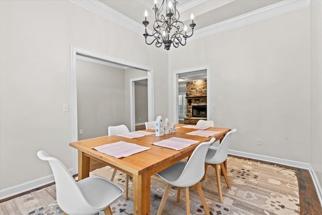dining area featuring wood finished floors, crown molding, baseboards, and an inviting chandelier
