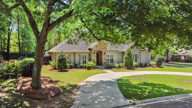 view of front facade featuring stucco siding, a front lawn, and fence