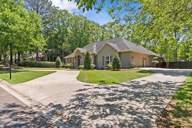 ranch-style home featuring driveway, fence, an attached garage, a front yard, and stucco siding