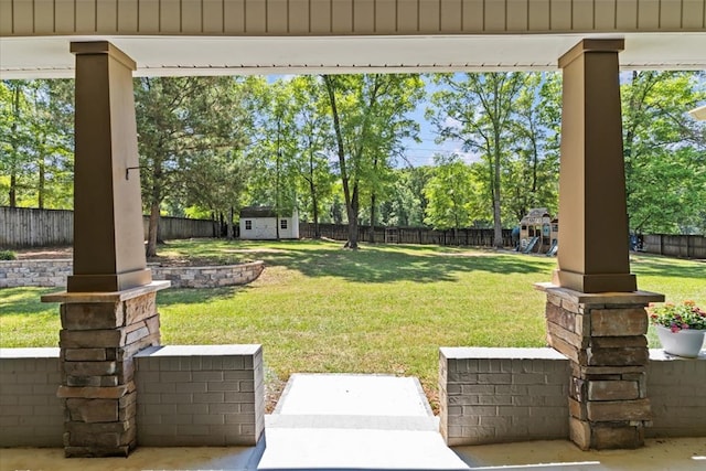 view of yard featuring a fenced backyard, an outbuilding, a storage shed, and a playground