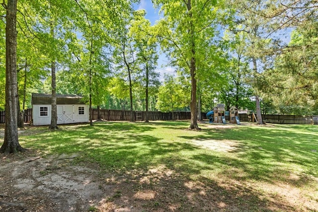 view of yard featuring a fenced backyard, a storage unit, an outbuilding, and a playground