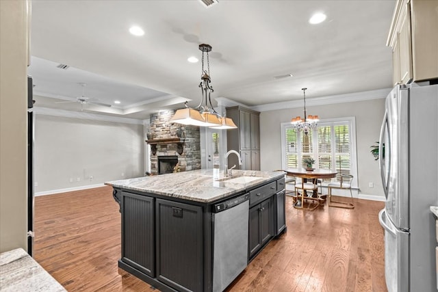 kitchen with a stone fireplace, ornamental molding, a sink, baseboards, and appliances with stainless steel finishes