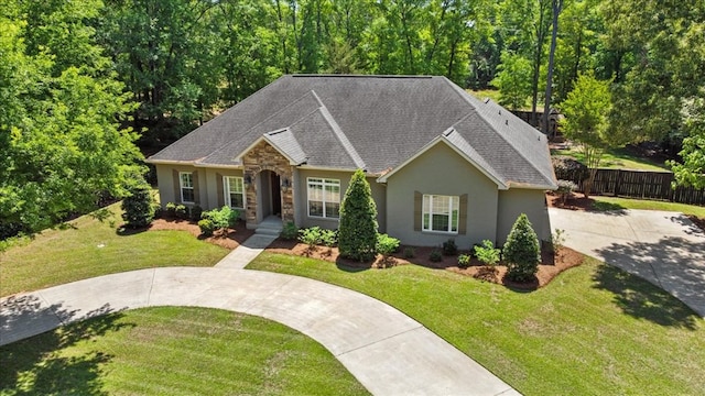 ranch-style home featuring roof with shingles, driveway, fence, a front yard, and stucco siding