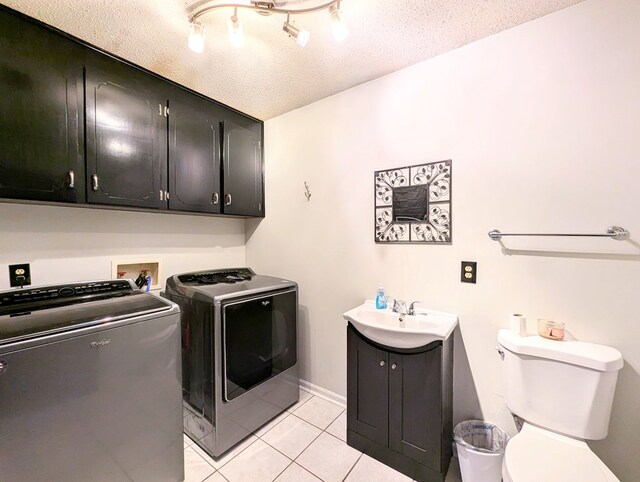 laundry area with sink, a textured ceiling, washing machine and dryer, and light tile patterned flooring