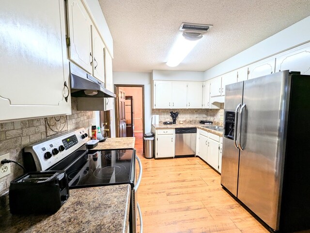 kitchen with backsplash, appliances with stainless steel finishes, a textured ceiling, white cabinets, and light wood-type flooring