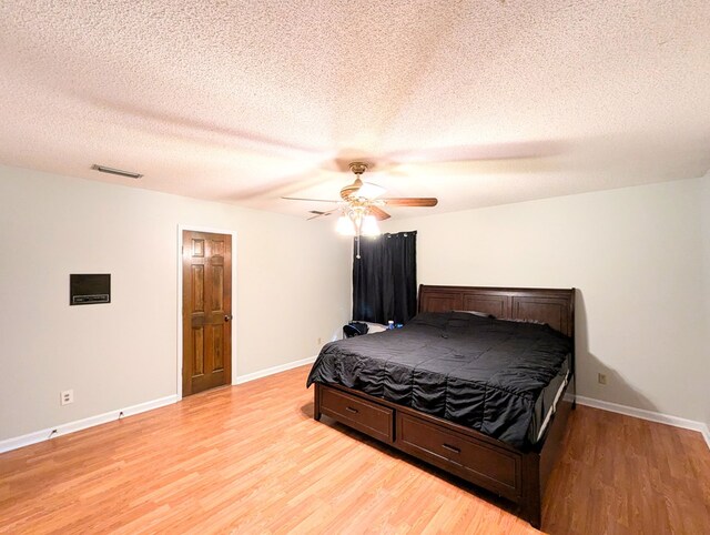 bedroom featuring ceiling fan, light hardwood / wood-style floors, and a textured ceiling