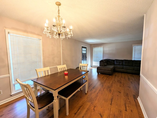 dining room featuring dark hardwood / wood-style flooring, a textured ceiling, and an inviting chandelier