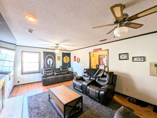 living room featuring ornamental molding, a textured ceiling, and light hardwood / wood-style flooring