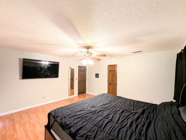 bedroom with ceiling fan, light hardwood / wood-style floors, and a textured ceiling