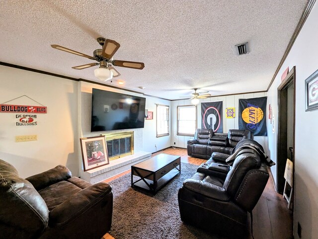 living room featuring hardwood / wood-style flooring, ceiling fan, a textured ceiling, and ornamental molding