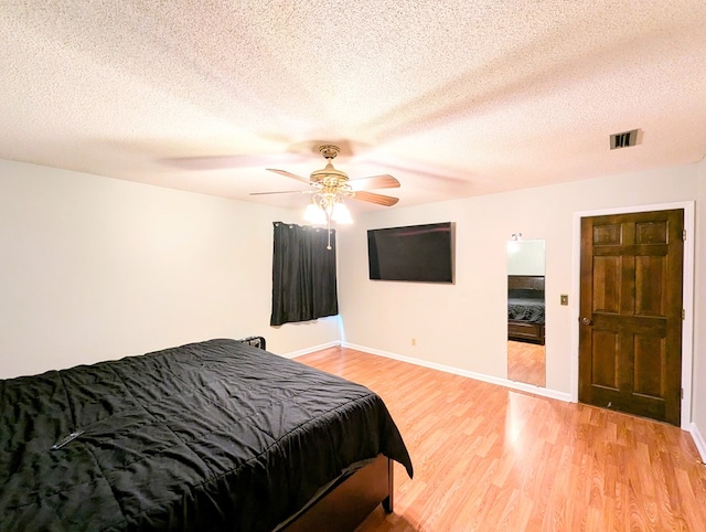 bedroom with a textured ceiling, light hardwood / wood-style flooring, and ceiling fan