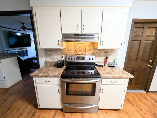 kitchen with tasteful backsplash, electric stove, and white cabinetry