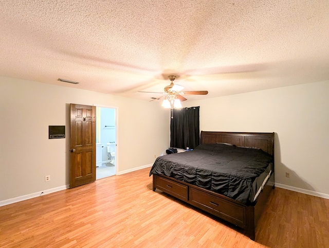 bedroom with ceiling fan, light wood-type flooring, a textured ceiling, and connected bathroom