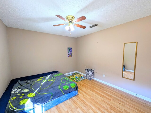 bedroom featuring ceiling fan, wood-type flooring, and a textured ceiling