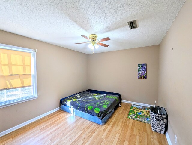 bedroom featuring hardwood / wood-style flooring, ceiling fan, and a textured ceiling