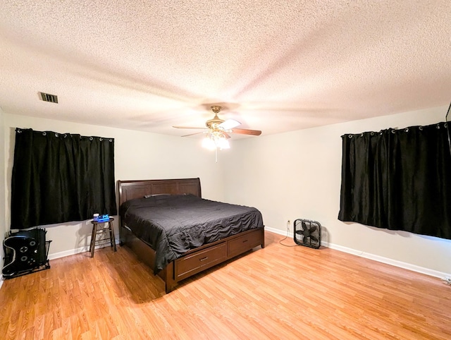 bedroom with a textured ceiling, light hardwood / wood-style floors, and ceiling fan