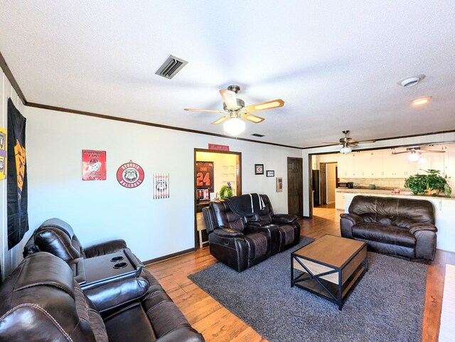 living room featuring a textured ceiling, light hardwood / wood-style floors, and crown molding