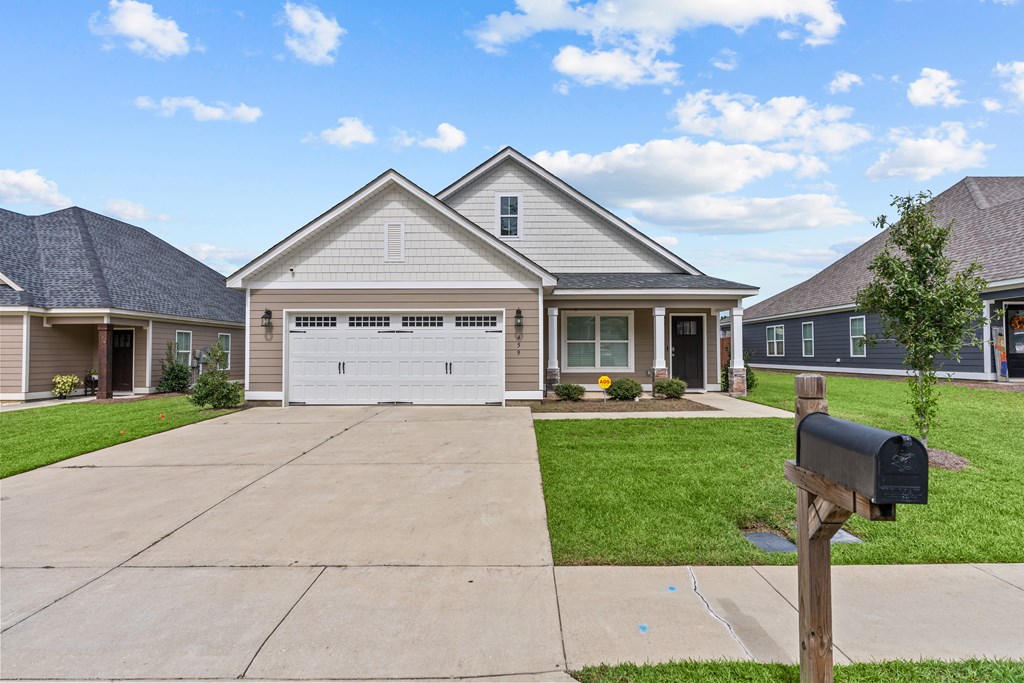 craftsman inspired home with driveway, a garage, and a front lawn