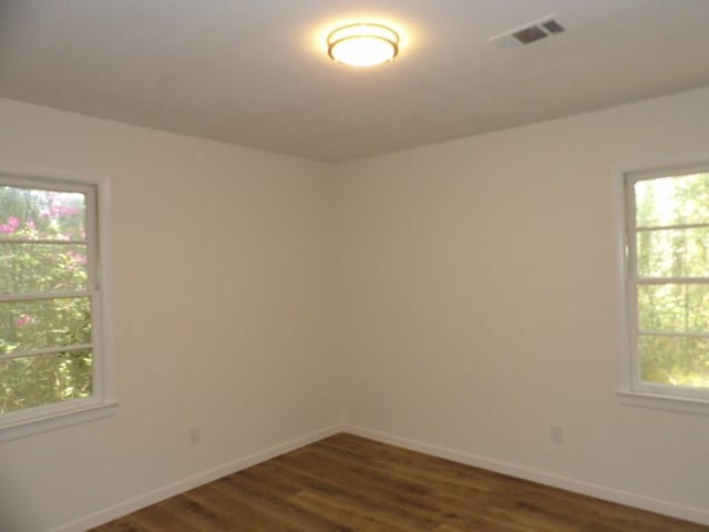 spare room featuring dark wood-type flooring, baseboards, and visible vents