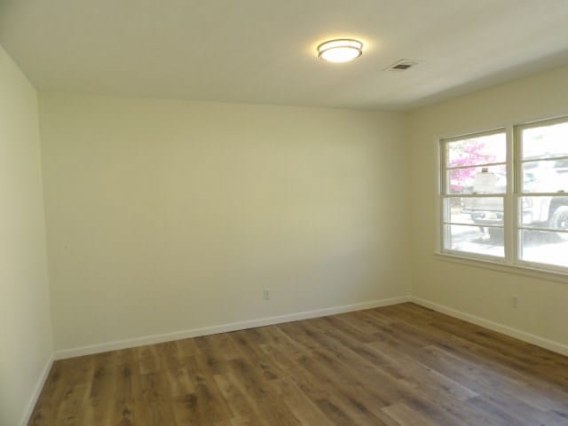 unfurnished room with baseboards and wood finished floors
