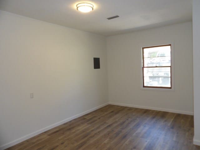 empty room featuring baseboards, visible vents, and wood finished floors