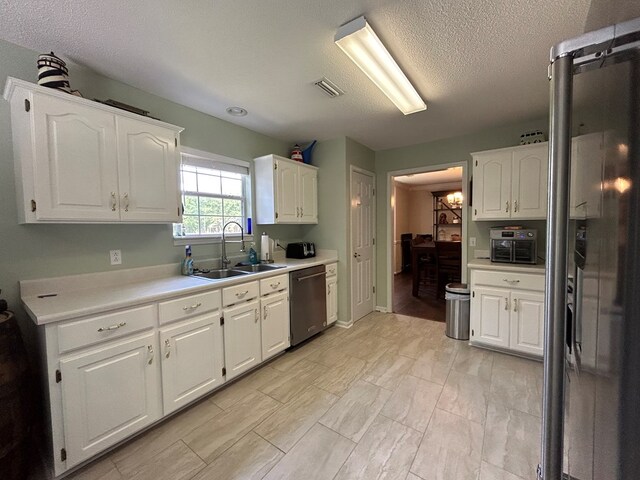 123 Waterford Way, Ashford, AL 36321 - kitchen with stainless steel dishwasher, a sink, white cabinetry, light countertops, and a textured ceiling
