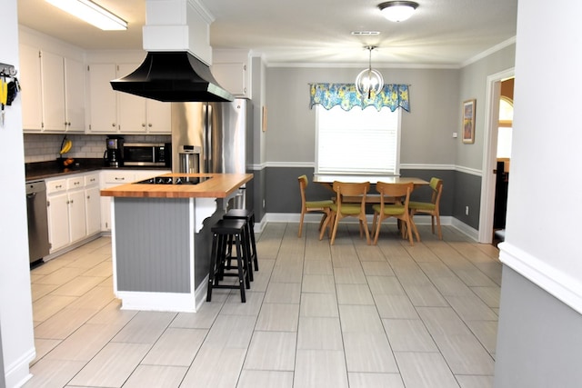 kitchen with extractor fan, wood counters, a breakfast bar, white cabinets, and appliances with stainless steel finishes