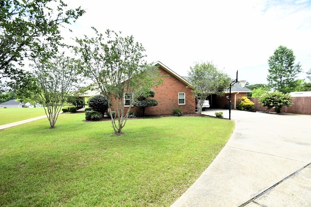 view of property exterior featuring fence, a lawn, a carport, brick siding, and driveway