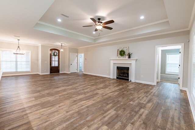 212 Archer Trl, Enterprise, AL 36330 - unfurnished living room featuring wood finished floors, ceiling fan with notable chandelier, a tray ceiling, a fireplace, and visible vents
