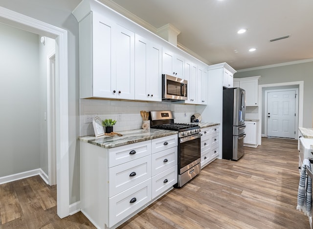 212 Archer Trl, Enterprise, AL 36330 - kitchen with stainless steel appliances, light wood-style flooring, white cabinetry, decorative backsplash, and ornamental molding