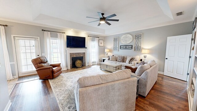 201 W Azalea Ln, Headland, AL 36345 - living area with a tray ceiling, ceiling fan, dark wood-style flooring, a tile fireplace, and ornamental molding