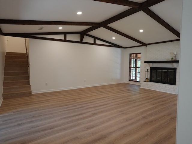 unfurnished living room with vaulted ceiling with beams, wood-type flooring, and a fireplace