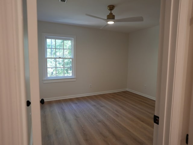 spare room with dark hardwood / wood-style flooring and ceiling fan