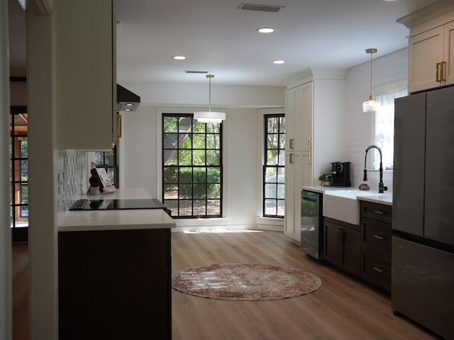 kitchen with pendant lighting, white cabinets, stainless steel appliances, and light hardwood / wood-style floors