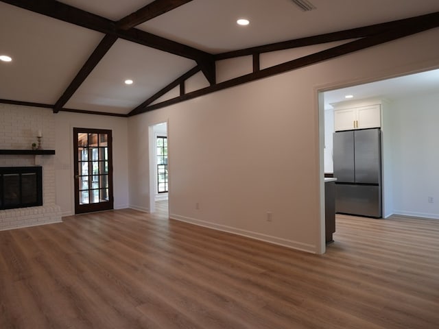 unfurnished living room with vaulted ceiling with beams, dark hardwood / wood-style flooring, and a brick fireplace