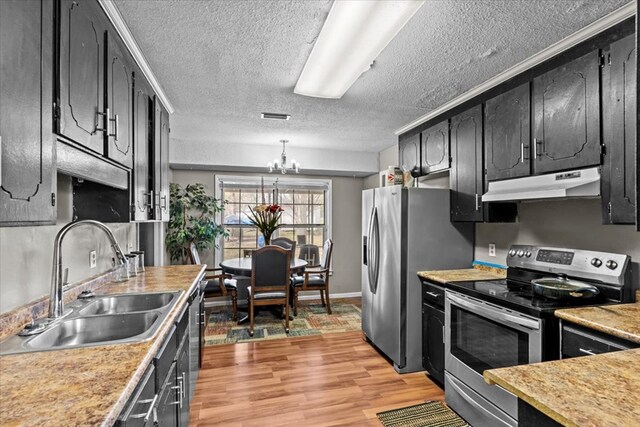 kitchen featuring a notable chandelier, appliances with stainless steel finishes, light wood-style floors, a sink, and under cabinet range hood