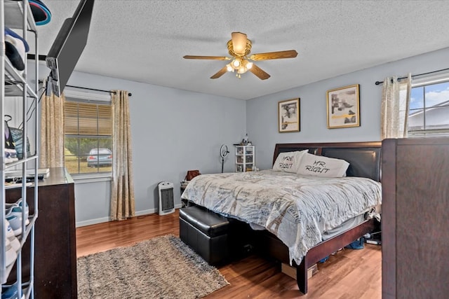 bedroom featuring ceiling fan, a textured ceiling, baseboards, and wood finished floors